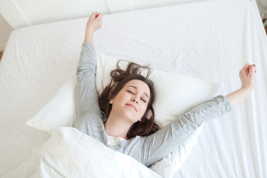 Young woman waking up fully rested on comfortable mattress.