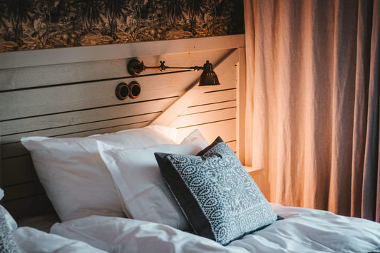 lamp turned on over a bed with lots of pillows