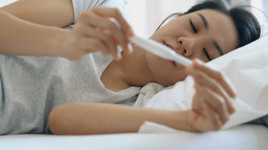 young woman lying down in bed holding a pregnancy test