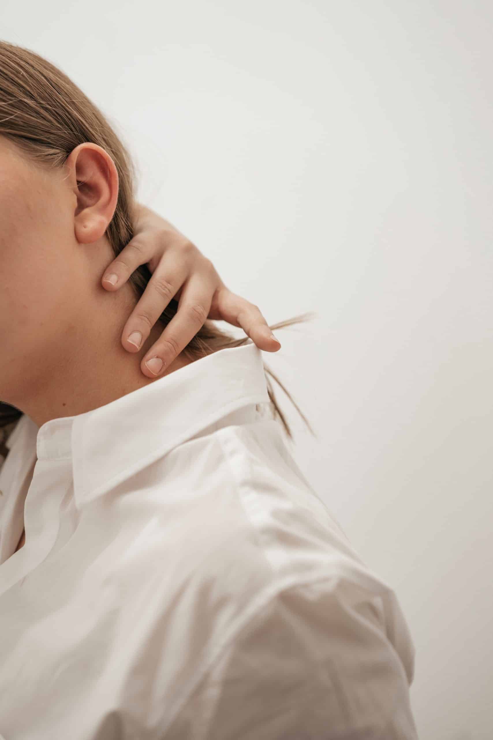 Woman reaching back to her neck in pain