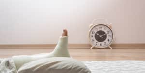 foot cast propped up on pillow with a clock in the background