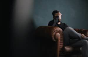 a man sitting on a leather couch holding his hand in his head