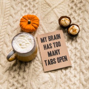 a fall-themed tablescape with a latte and pumpkin and sign that says my brain has too many tabs open