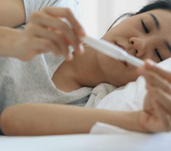 young woman lying down in bed holding a pregnancy test