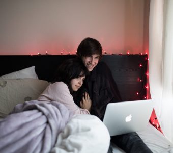 Image of a young cool couple in bed watching content on an apple computer on a Mattress World Northwest Couples Mattress