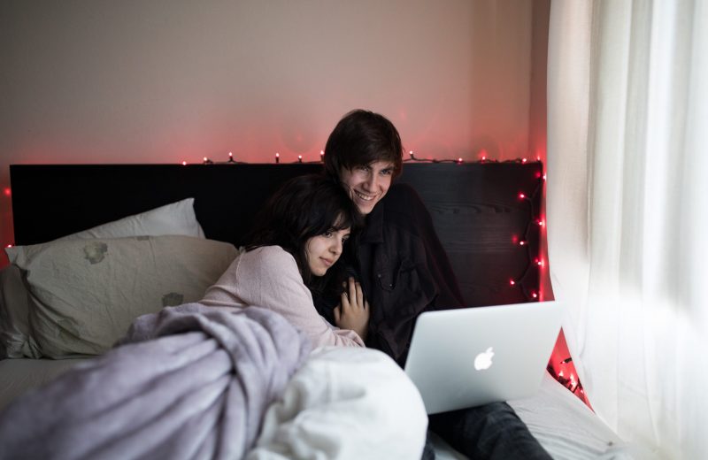 Image of a young cool couple in bed watching content on an apple computer on a Mattress World Northwest Couples Mattress