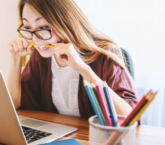 Image of a woman over a computer biting a pencil
